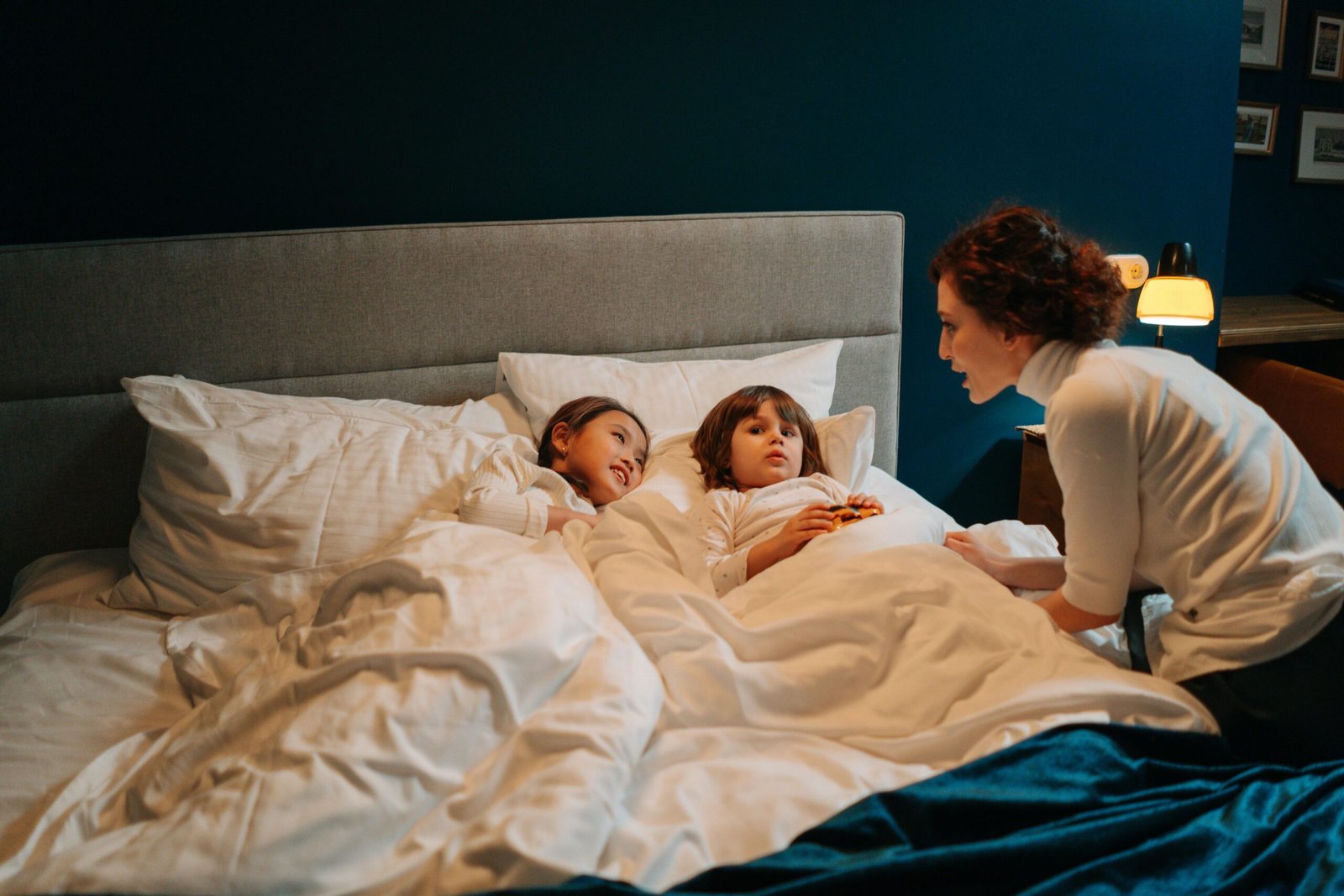 A nanny telling a bedtime story to two children in a cozy bedroom setting.